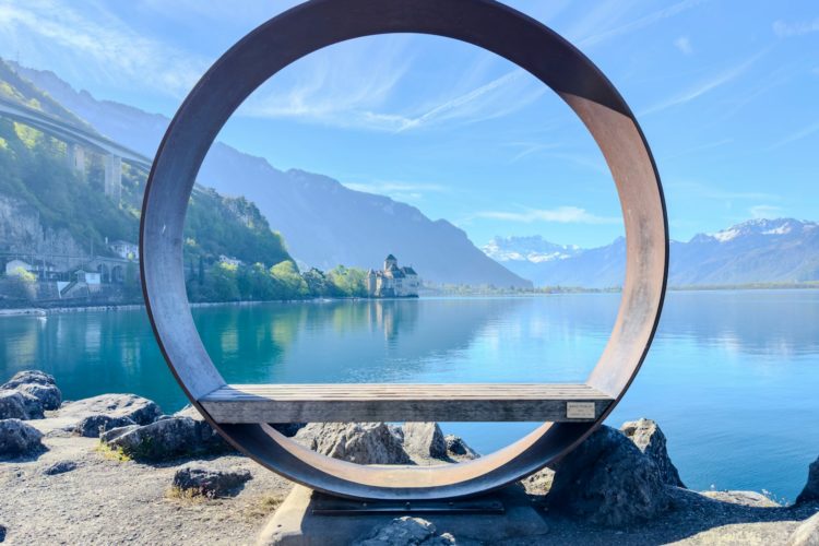 a circular sculpture sitting on top of a rock near a body of water