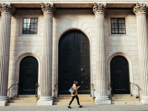 woman walking in-front of white building with ionic pillars